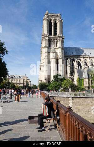 Accordion player at Pont au double, Notre-Dame Cathedral in fourth arrondissement, Ile de la Cite, Paris. France. Stock Photo