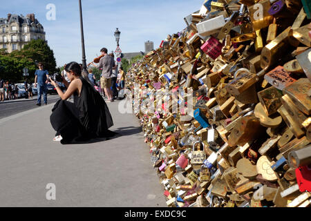 Asian girl photographing Love locks, lockers, symbolizing forever lasting love, at Pont de l'Archeveche, Paris, France. Stock Photo