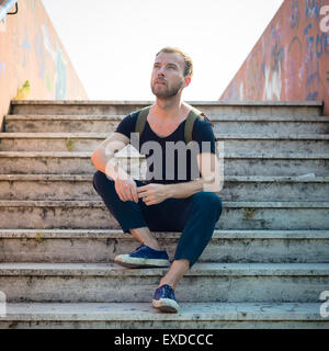 hipster modern stylish blonde man sitting in stairs in daily life Stock Photo