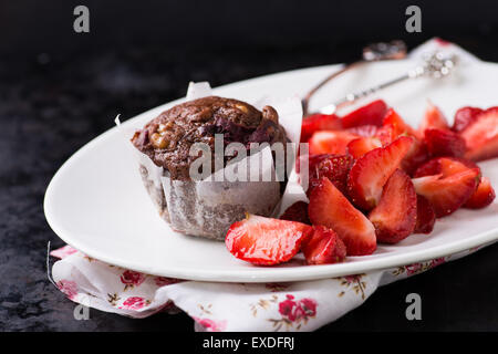Chocolate muffins with nuts and cherry, strawberries on side, metal background, selective focus Stock Photo