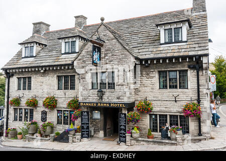 Corfe village in England. Grey limestone and slate roof building, the Bankes Arms Hotel, sited on street corner. Flower baskets hanging from 2nd story. Stock Photo