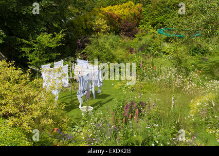 Washing hanging to dry on rotary airer washing line in flower filled family wildlife garden in Scotland, UK Stock Photo
