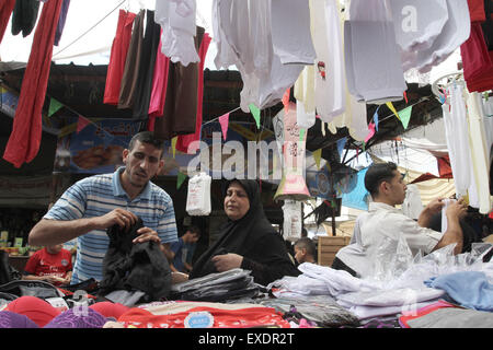 Jabalia, The Gaza Strip, Palestine. 12th July, 2015. Palestinian worker sale new clothes for Eid Al Fitr at Jabalia refugee camp market northern the Gaza Strip. © Mahmoud Issa/Quds Net News/ZUMAPRESS.com/Alamy Live News Stock Photo