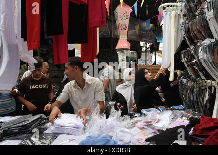 Jabalia, The Gaza Strip, Palestine. 12th July, 2015. Palestinian worker sale new clothes for Eid Al Fitr at Jabalia refugee camp market northern the Gaza Strip. © Mahmoud Issa/Quds Net News/ZUMAPRESS.com/Alamy Live News Stock Photo