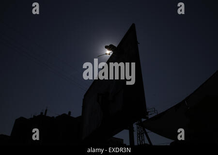 Gaza City, The Gaza Strip, Palestine. 12th July, 2015. Palestinian worker hang banner congratulates Gazans by Eid al-Fitr at Gaza City. © Mahmoud Issa/Quds Net News/ZUMAPRESS.com/Alamy Live News Stock Photo