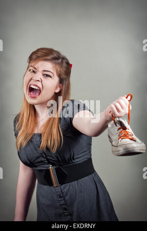 Cute girl holds up smelly stinky sneaker shoe and screams Stock Photo