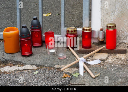 Marsberg, Germany. 12th July, 2015. Candles and two crossed sticks were laid down in front of the gate leading to the hall of the marksmen association in Marsberg, Germany, 12 July 2015. A man was hit and a window was smashed by a metal part of a cannon on 11 July 2015. The cannon barrel burst during a firing of the cannon, which hit a champion marksman and smashed a window. The champion marksman was killed in the incident. Photo: BERND THISSEN/dpa/Alamy Live News Stock Photo