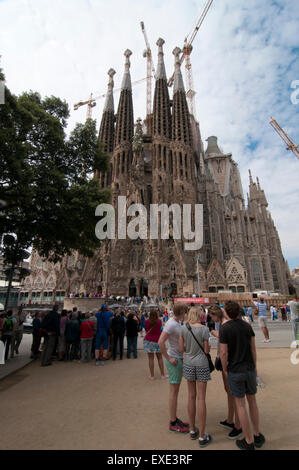 Tourists looking at the Nativity Facade of the La Sagrada Familia from Placa de Gaudi gardens Stock Photo