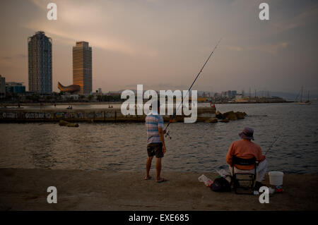 Barcelona, Catalonia, Spain. 12th July, 2015. Two men wait for the fish to bite on the breakwater of Barcelona as the sun sets on a summer Sunday. © Jordi Boixareu/ZUMA Wire/Alamy Live News Stock Photo