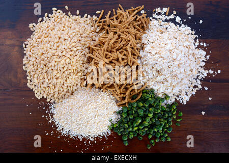 Stack of Healthy High Fiber Prebiotic Grains including wheat bran cereal, oat flakes and pearl barley, on rustic dark wood table Stock Photo