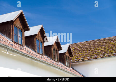 Tile roof and windows of mansard rooms against blue sky Stock Photo