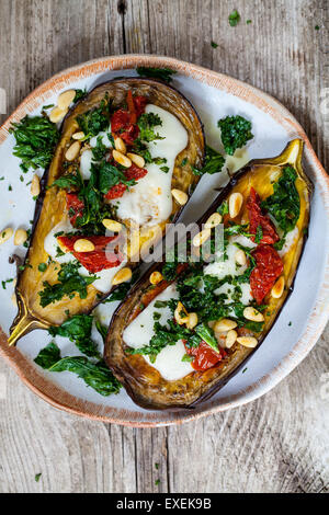 Roast aubergine with goat cheese, crispy kale, sun dried tomatoes and pine nuts Stock Photo