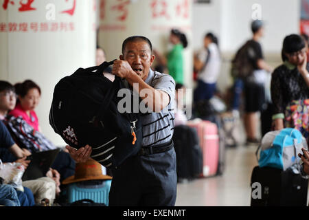 Lanzhou, China's Gansu Province. 13th July, 2015. A passenger carrying luggages waits for a train at Lanzhou Railway Station in Lanzhou, capital of northwest China's Gansu Province, July 13, 2015. Lanzhou Railway Station recently witnessed its first travel peak this summer. © Chen Bin/Xinhua/Alamy Live News Stock Photo