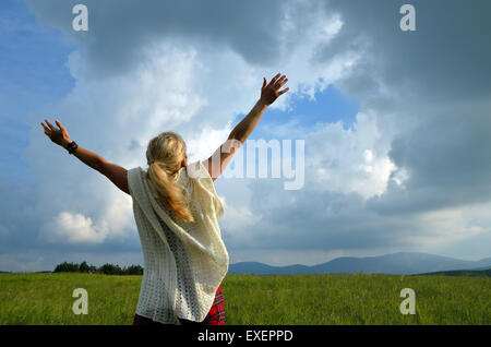 Happy and joyful woman spreading hands to the sky and showing love for nature Stock Photo