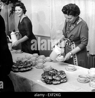 Queen Juliana and Princess Beatrix of the Netherlands serve the palace staff during a Christmas gathering, highlighting the royal family's tradition of humility and connection with their workers during the holiday season. Stock Photo