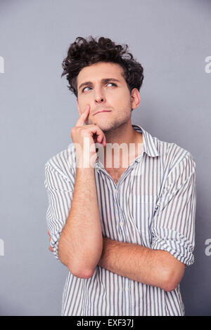 Portrait of a young pensive man looking away over gray background Stock Photo