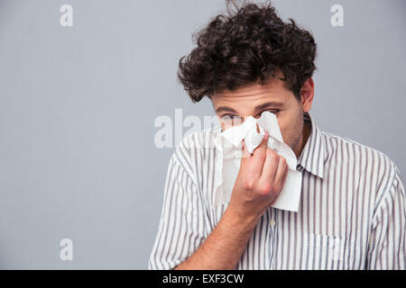 Portrait of a man blowing his nose over gray background Stock Photo