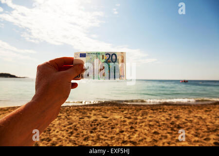 Euro currency note 20 money cash hand against sky beach holiday holidays on vacation sea coast Ibiza Spain Spanish resort Stock Photo