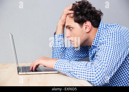 Side view portrait of a serious man sitting at the table and using laptop Stock Photo
