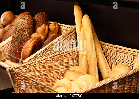 Baskets with various kinds of fresh baked bread on the shelf in the store. Stock Photo
