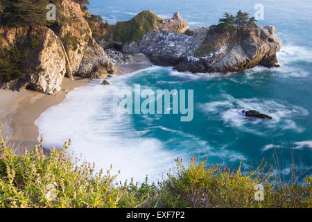 Waterfall in Julia Pfeifer Burns State Park at sunset with a soft golden color on the rocks Stock Photo