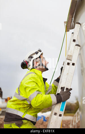 Engineer climbing ladder, working on wind turbine Stock Photo