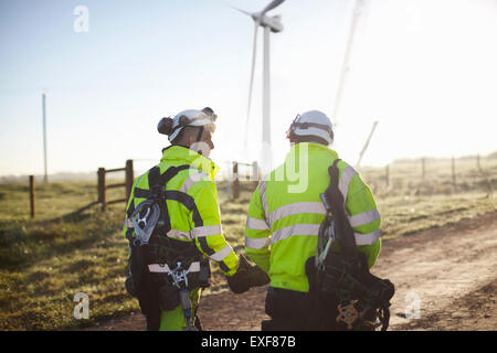 Two engineers at wind farm, walking together, rear view Stock Photo