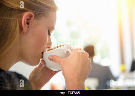 Young woman drinking coffee in cafe, close-up Stock Photo