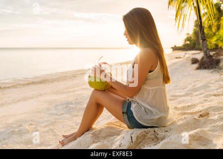 Young woman drinking coconut milk on Anda beach, Bohol Province, Philippines Stock Photo