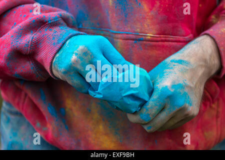 A close-up of blue colored men's hand grabbing a powder from a small bag during a Color festival. Stock Photo