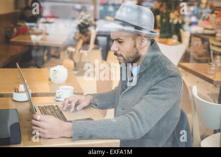Businessman sitting in front of cafe window using laptop Stock Photo