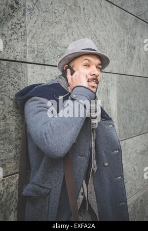 Businessman leaning against wall talking on smartphone Stock Photo