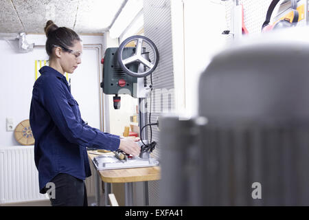 Young female carpenter drilling timber in workshop Stock Photo