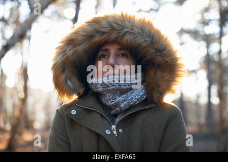 Portrait of mature woman wearing fur hood and scarf in forest Stock Photo