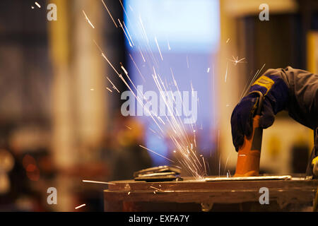 Sparks from worker using grinder in factory Stock Photo