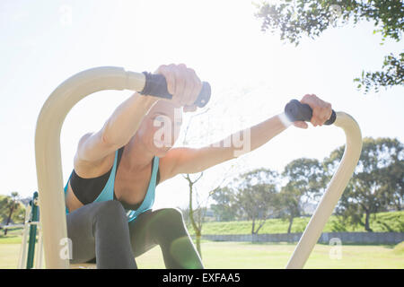 Mid adult woman training on rowing machine in park Stock Photo