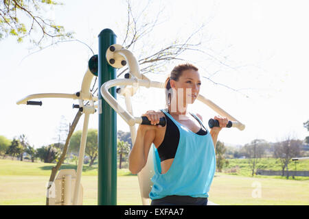 Mid adult woman in park training on weight machine Stock Photo