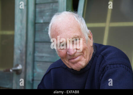 Senior man sitting, relaxing, outside shed Stock Photo