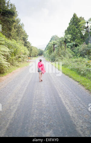 Woman walking away on straight road Stock Photo