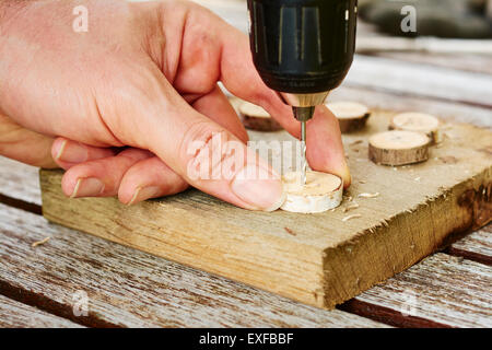Man drilling holes into wooden buttons. Stock Photo