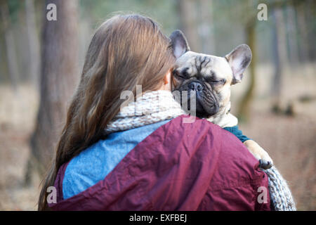 Portrait of cute dog being carried through forest by young woman Stock Photo