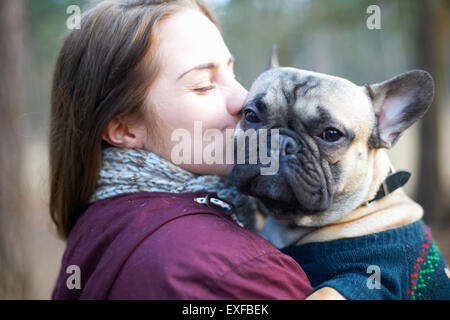 Portrait of wise dog being carried through forest by young woman Stock Photo