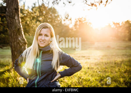 Portrait of young woman in sunlit park Stock Photo