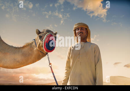 Portrait of camel and bedouin in desert, Dubai, United Arab Emirates Stock Photo