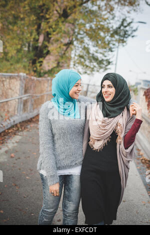 Two young female friends walking and chatting on park path Stock Photo