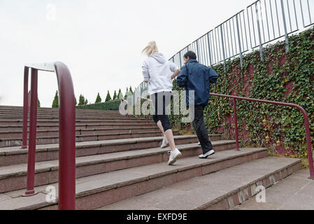 Man and woman running up steps together, rear view Stock Photo