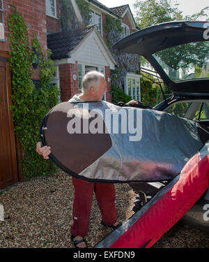 Senior man loading surfboard into car boot Stock Photo