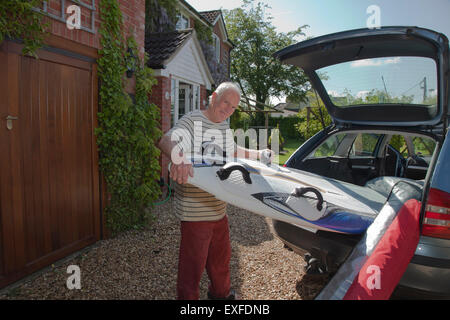 Senior man removing surfboard from car boot Stock Photo