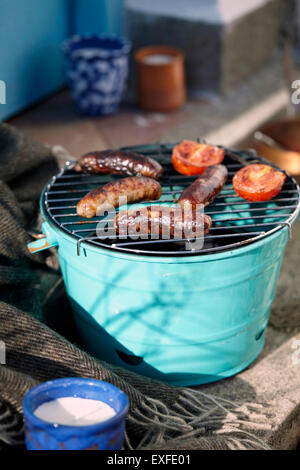 Barbecue with sausages and tomatoes on doorstep Stock Photo
