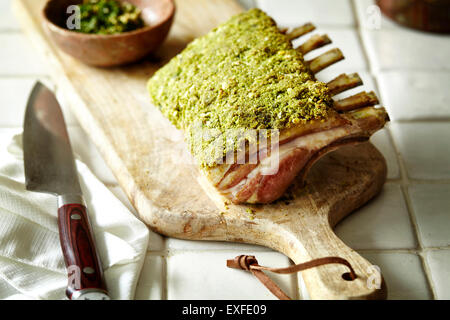 Rack of lamb with herb crust on chopping board Stock Photo